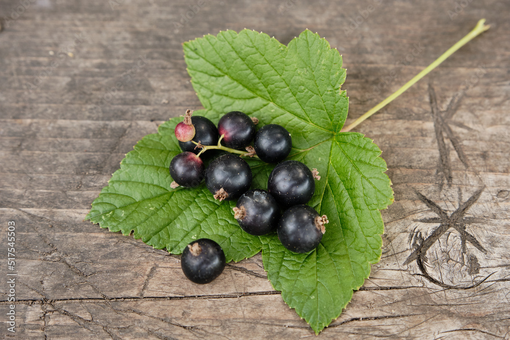 Blackcurrants with green leaves on the wooden table. Blackcurrants with green leaves on the wooden table.
