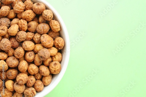 Chufa, tigernut, earth almond on ceramic bowl on green background with copy space for text. Healthy organic food concept. Tiger nut for flour, milk, traditional typical drink horchata Valencia Spain photo