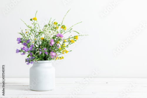 Fotografia, Obraz Beautiful bouquet of wild summer flowers in vase against white wall
