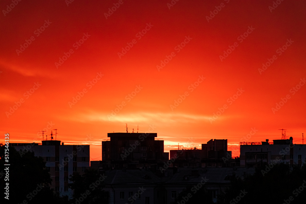 Silhouette of the city at sunset. Sun is rising over tall buildings.