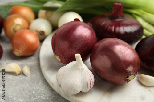 Fresh onion bulbs, leek and garlic on grey table, closeup