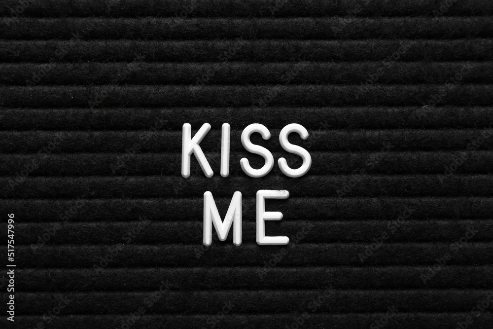 Phrase Kiss Me on black textured surface Phrase Kiss Me on black textured surface