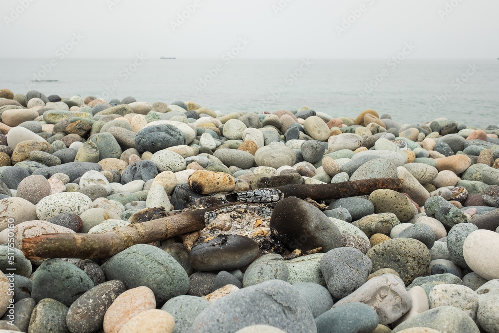 Burnt bonfire on the beach. Rubbish after night campfire on stones Burnt bonfire on the beach. Rubbish after night campfire on stones