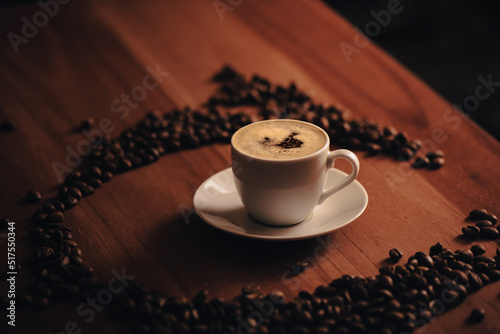 Taza de caf    taza blanca  rodeado de granos de caf    en mesa de madera  mesa de caf    en la ma  ana