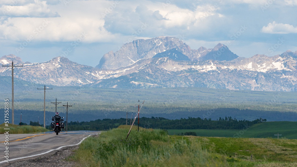 A lone motorcyclist riding toward the Grand Teton mountains on the Idaho side of the range.