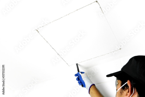 Using a handsaw cutting to cut a hole in the ceiling to install the service port.              photo