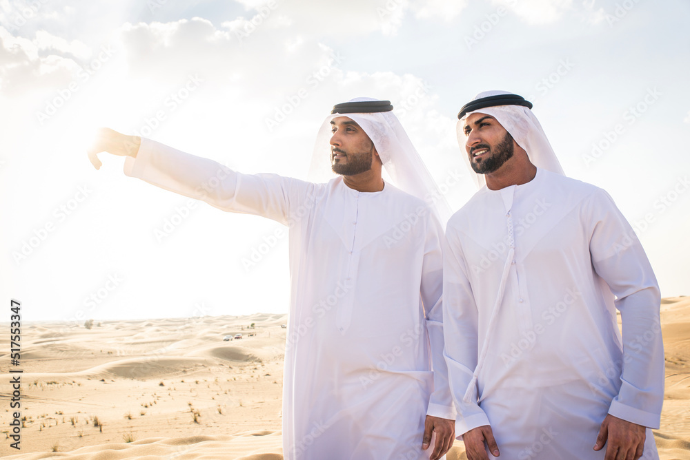 Arabic men in the desert of Dubai wearing traditional emirates clothing