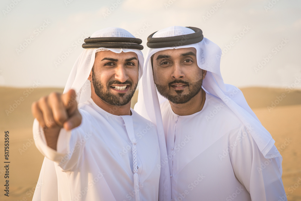 Fototapeta premium Arabic men in the desert of Dubai wearing traditional emirates clothing