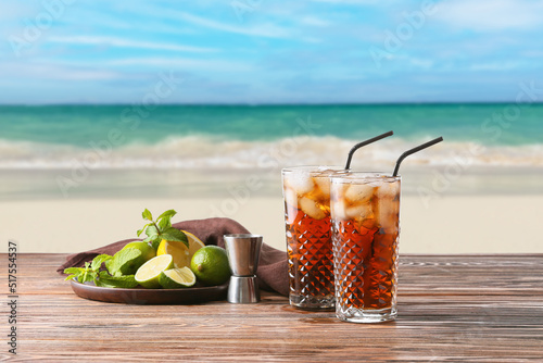 Canvas Print Glasses of tasty Cuba Libre cocktail and ingredients on table at sea resort