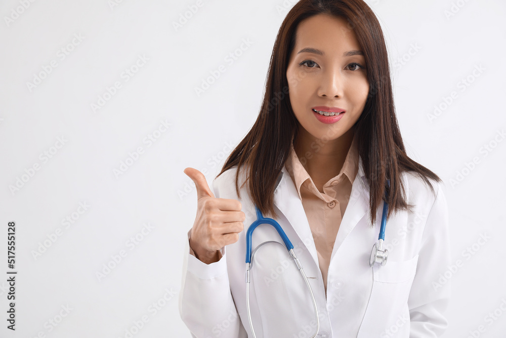 Female Asian doctor showing thumb-up on white background Female Asian doctor showing thumb-up on white background