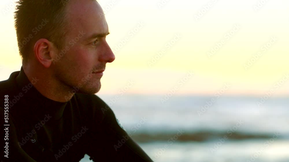 Handsome male surfer in a wetsuit by the beach. Mature man thinking while waiting for the current, tide and waves to surf in the sea or ocean. Enjoying his recreational hobby time at the beach Handsome male surfer in a wetsuit by the beach. Mature man thinking while waiting for the current, tide and waves to surf in the sea or ocean. Enjoying his recreational hobby time at the beach