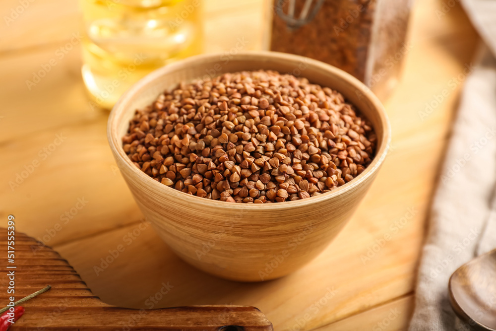 Bowl with dry buckwheat grains on wooden table Bowl with dry buckwheat grains on wooden table