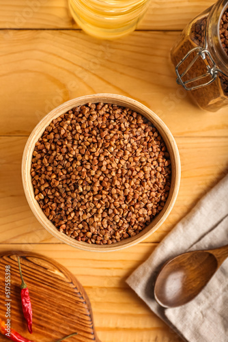 Bowl with dry buckwheat grains on wooden table