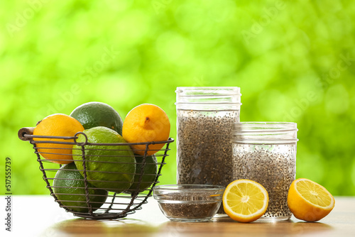 Glasses of water with chia seeds, citrus fruits and bowl on table outdoors