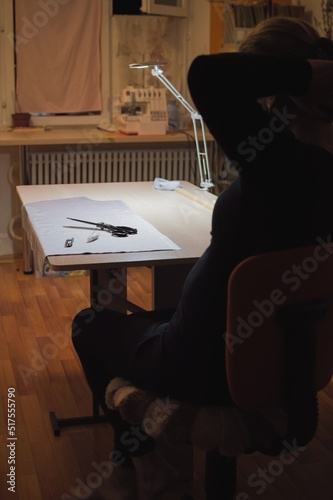 Dressmaker relaxing sitting on chair, lighted table