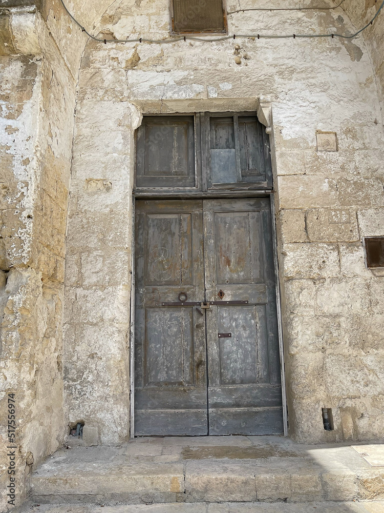 ancient wooden brown doors on the side of ancient white stone building