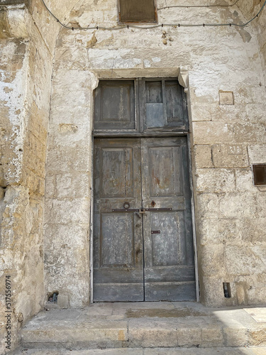 ancient wooden brown doors on the side of ancient white stone building