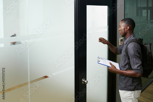 Foto Serious software developer with CV in hands knocking at door of compnay HR manag