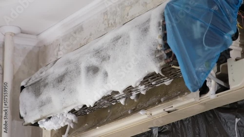 A man sprays special foam to clean air conditioners on the radiator. Split system maintenance.