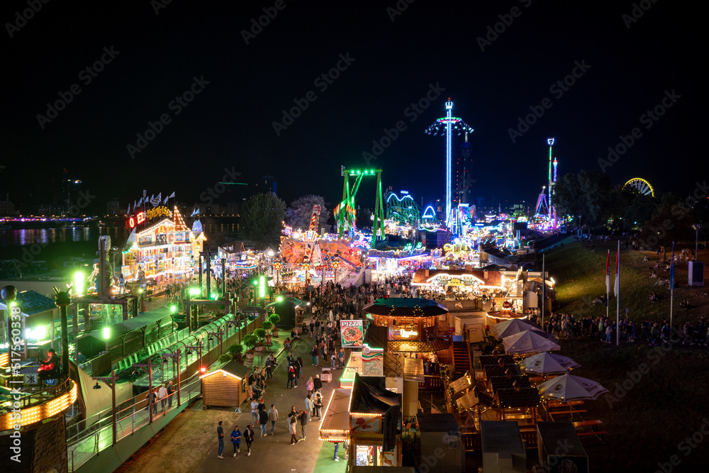 Naklejka premium Aerial top view of amusement park, carnival or festival called Größte Kirmes am Rhein, with crowd of visitors during night time.