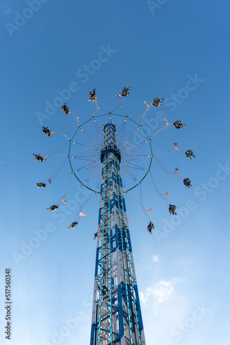 Low angle view of Star flyer, Chain carousel amusement ride, move up and down, and spin around the top of tower with beautiful decorated light against blue sky. photo