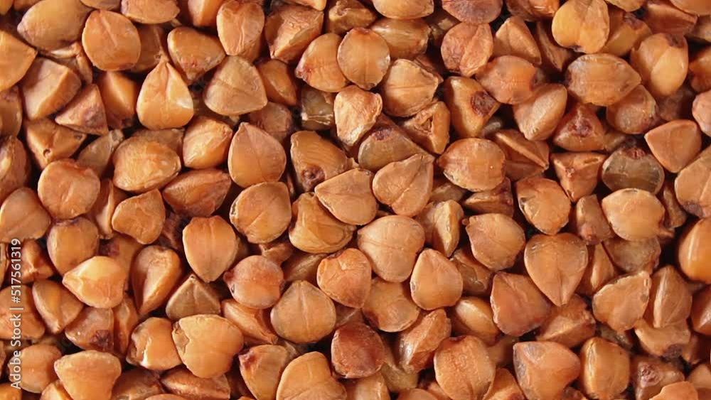 Dry Uncooked Brown Buckwheat Groats, Slowly Rotating Background - Top View, Close-Up, Macro. Raw Large Buckwheat Grains. Russian, Ukrainian and Belarusian Culture. Rotation Left Dry Uncooked Brown Buckwheat Groats, Slowly Rotating Background - Top View, Close-Up, Macro. Raw Large Buckwheat Grains. Russian, Ukrainian and Belarusian Culture. Rotation Left