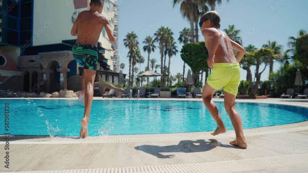 Brothers jumping in the water. Two boys fun jumping into swimming pool.