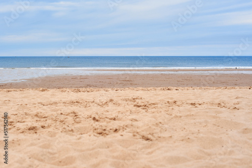 Beautiful seascape with perfect yellow sand and overcast blue sky. Paradise holiday. Perfect deserted beach for nudists. Sunny beaches of England. Ukrainian flag