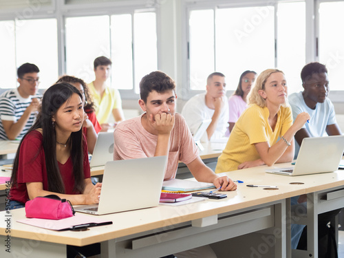 Group of multi-ethnic teenage student listening to the lesson in class in a classroom with computers. Education and technology, back to school