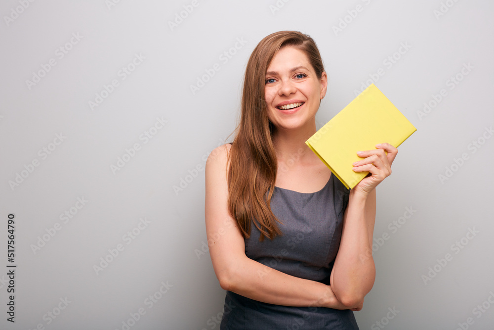 Smiling business woman in gray dress holding yellow book. isolated female business person portrait. Smiling business woman in gray dress holding yellow book. isolated female business person portrait.