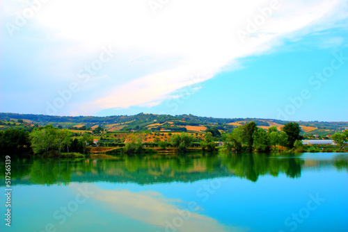 Calm view from the park  I Due Laghi  in Piane di Moresco with the clear pure waters of the lake mirroring some stunning green trees and the characteristic Marche hilly landscape in the background