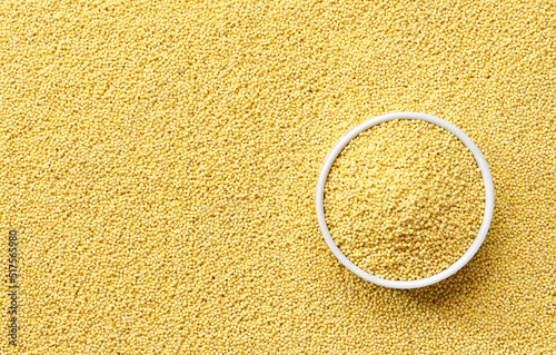 ceramic plate with dry millet groats on a millet yellow grains background close-up top view. photo