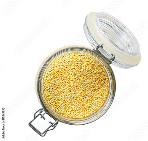 Heap of uncooked dry millet groats in glass storage jar isolated on white background top view.