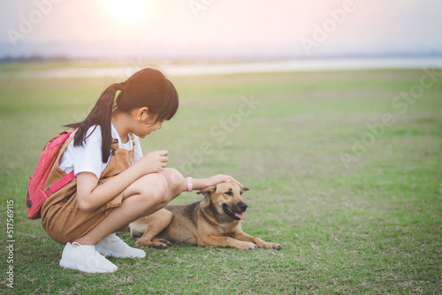 The little girl is stroking her dog with gently and friendly, showing love and care of pet