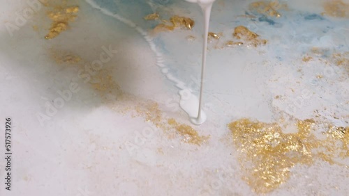 Close-up of pouring white-colored paint on the canvas. mixing acrylic paints with epoxide resin in fluid art technique. photo