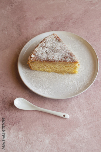Delicioso Trozo de pastel sobre un plato redondo a un lado una cucharita blanca en un fondo rosado, vintage photo