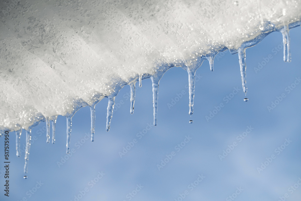 Melting ice. Icicles hang under the roof and drip under the spring sun. Copy space Melting ice. Icicles hang under the roof and drip under the spring sun. Copy space