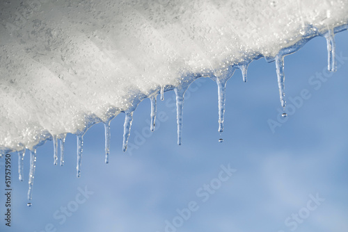 Melting ice. Icicles hang under the roof and drip under the spring sun. Copy space