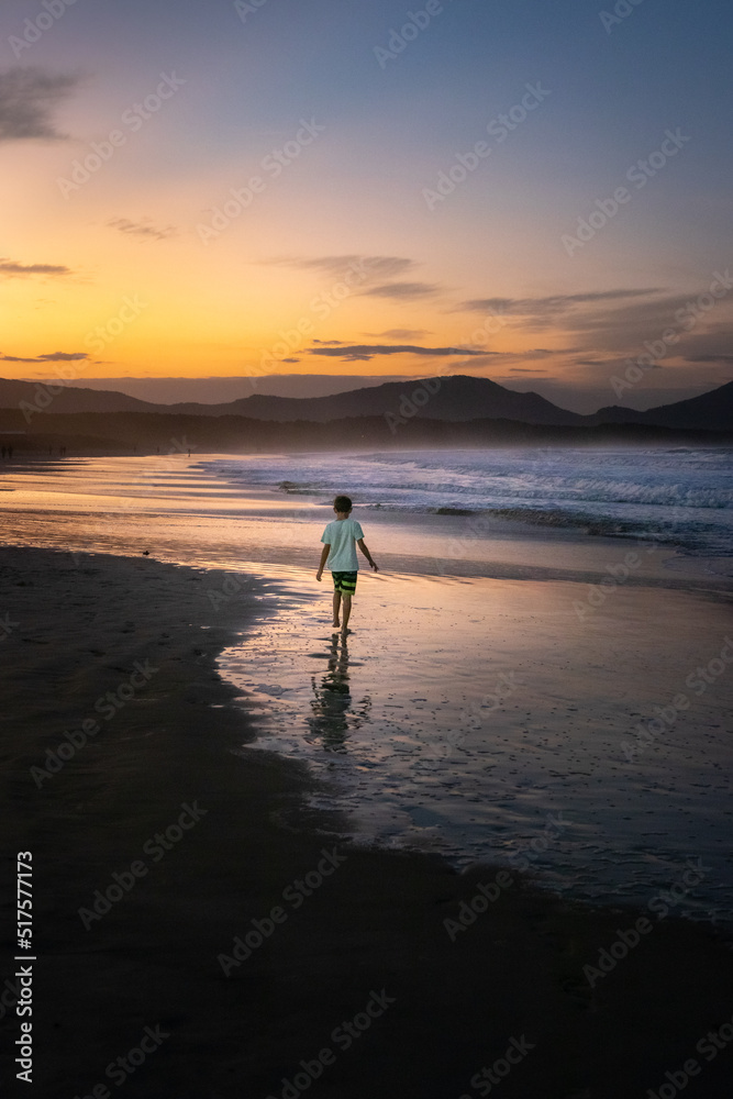 boy running on the beach at sunset