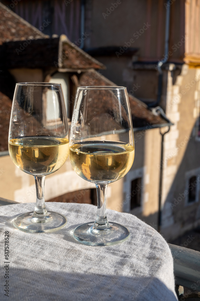 Obraz premium Tasting of white grand cru classe chablis wine with old French houses on background, Burgundy, France