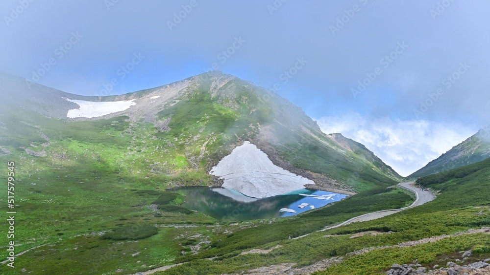Fototapeta premium 富士見岳から見おろす霧に包まれた雪渓と不消ヶ池のコラボ情景＠長野