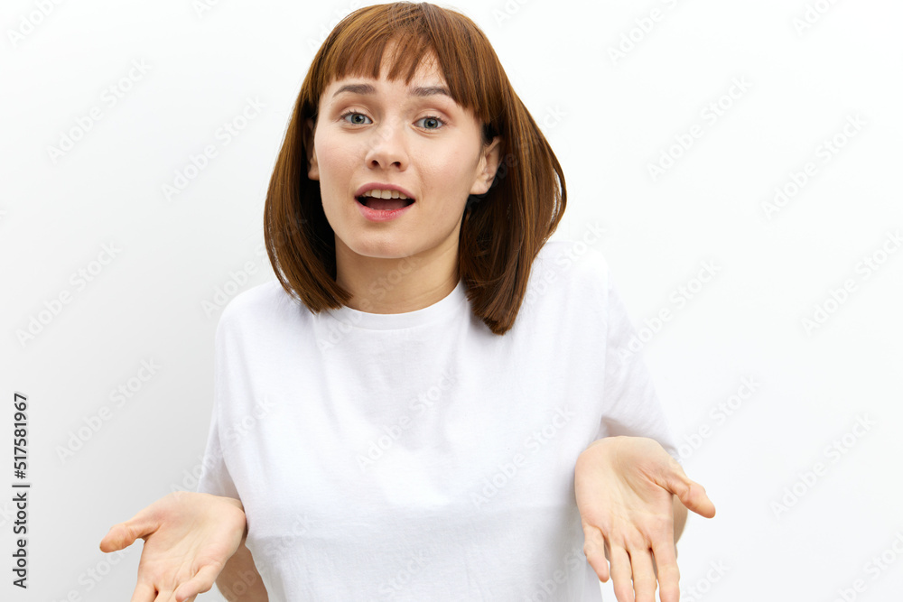 a beautiful, sweet, attractive woman stands on a white background in light clothes and spreads her hands in surprise. Horizontal photo with an empty space for inserting an advertising layout a beautiful, sweet, attractive woman stands on a white background in light clothes and spreads her hands in surprise. Horizontal photo with an empty space for inserting an advertising layout