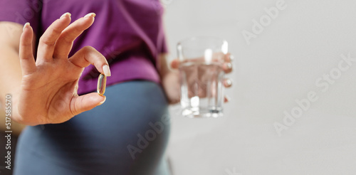 pregnant woman drinks pills. Pregnant woman holding a glass of water and vitamins for pregnant women in her hands, focus on the hand. Pregnancy health concept
