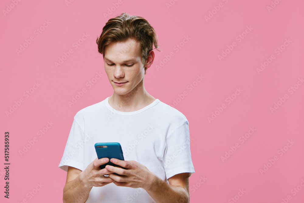cute nice guy with a thoughtful smile typing a text message on the phone cute nice guy with a thoughtful smile typing a text message on the phone