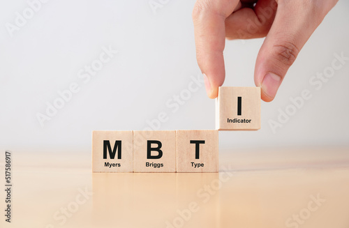 Psychological and personality test concept, Hand puts wooden cubes with MBTI, Myers-Briggs Type Indicator on table.