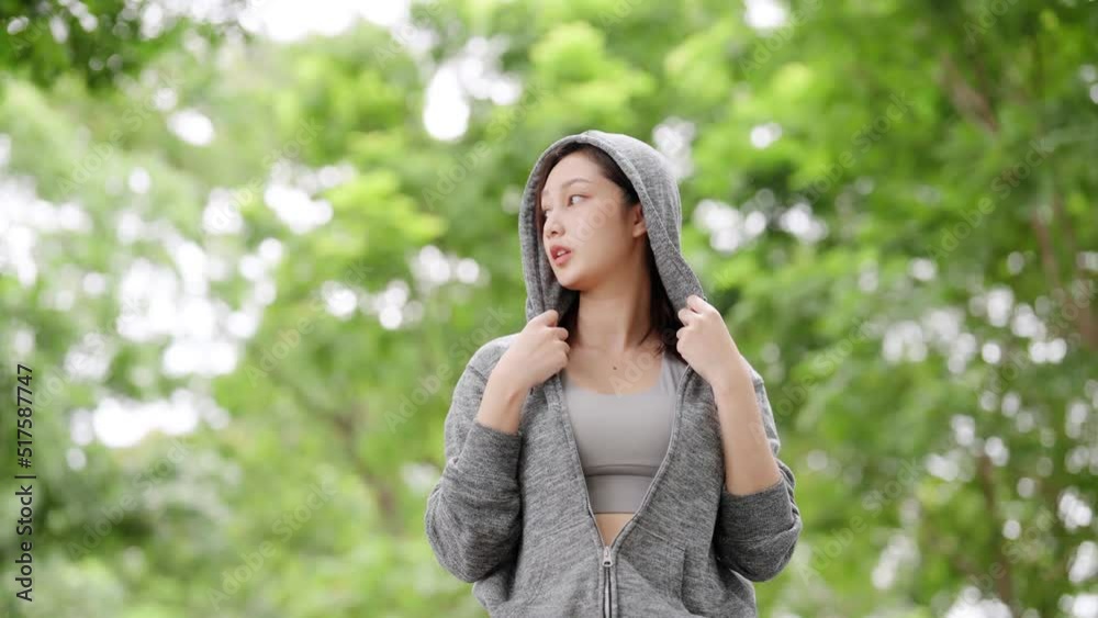 Asian woman wearing jacket is engaged in fitness in public park. Healthy lifestyle concept, sports outdoor activities in park Asian woman wearing jacket is engaged in fitness in public park. Healthy lifestyle concept, sports outdoor activities in park