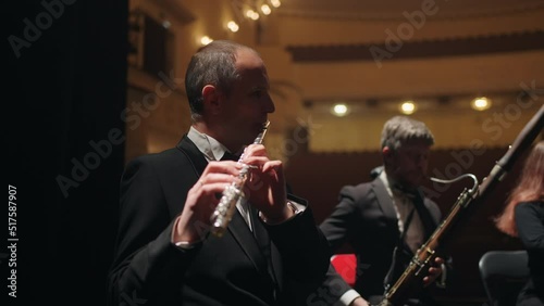 bassoonist and flutist are playign music in orchestra, musicians on scene of opera house photo