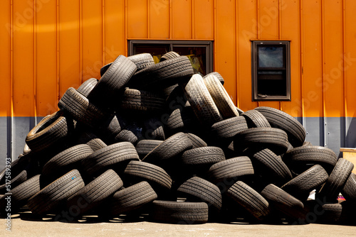 Stacked tires await disposal outside of a tire repair shop.