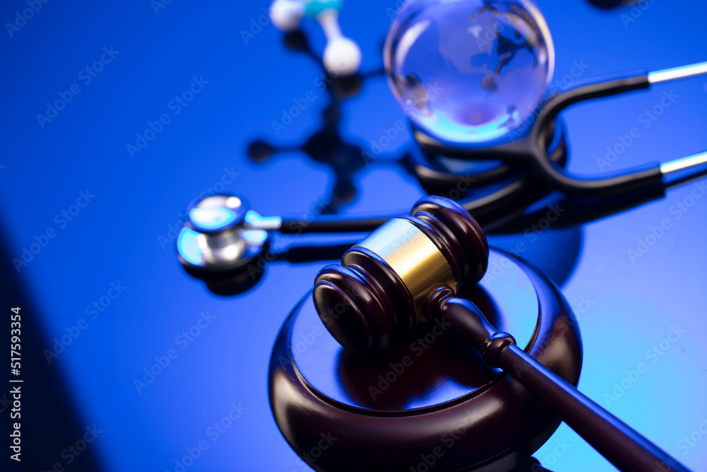 Medical law concept. Gavel, legal code and stethoscope on the glass table. Blue light. Medical law concept. Gavel, legal code and stethoscope on the glass table. Blue light.