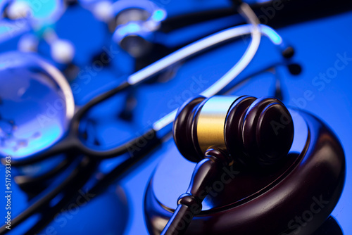 Medical law concept. Gavel, legal code and stethoscope on the glass table. Blue light.